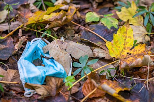 Discarded Corona mask Garbage in the dirt in colorful autumn leaves in Germany Garbage problem