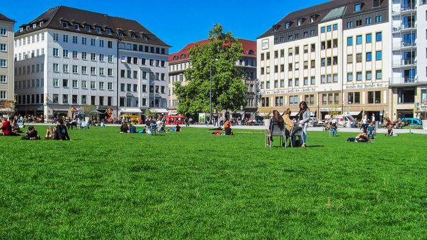 Germany, Munich - September 21, 2015: Young people relax on a green lawn in the city