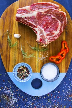 Raw beef meat on the table, spices and Rosemary, Rib eye steak ingredients. Pepper and coarse salt