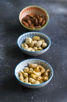 Nuts mix, beer snack on the bowl. Studio shoot. Cashews and coasted nuts on the blue background. Colorful nuts set.