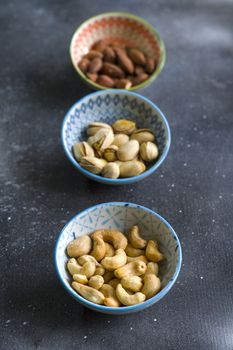 Nuts mix, beer snack on the bowl. Studio shoot. Cashews and coasted nuts on the blue background. Colorful nuts set.