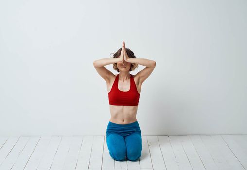 A slender woman is engaged in yoga for beginners on a light background in full growth. High quality photo