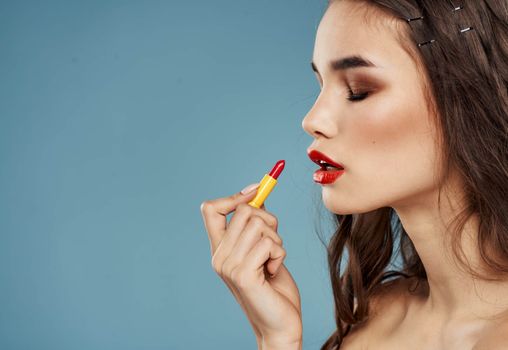 Red lipstick on blue background and brunette model female hands cropped view. High quality photo
