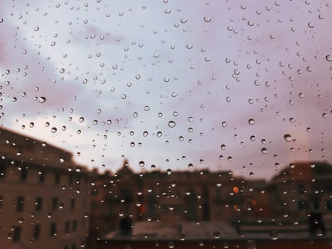 Genova, Italy - 10/22/2020: Water​ rain​ drops​ on​ glass​ background.​ Rain​ drops​ on​ a​ Windows. Hdden sunset in autumn after rain.