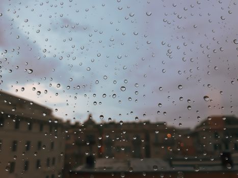 Genova, Italy - 10/22/2020: Water​ rain​ drops​ on​ glass​ background.​ Rain​ drops​ on​ a​ Windows. Hdden sunset in autumn after rain.