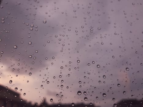 Genova, Italy - 10/22/2020: Water​ rain​ drops​ on​ glass​ background.​ Rain​ drops​ on​ a​ Windows. Hdden sunset in autumn after rain.