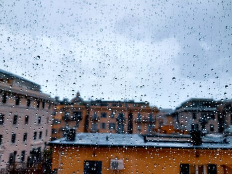 Genova, Italy - 10/22/2020: Water​ rain​ drops​ on​ glass​ background.​ Rain​ drops​ on​ a​ Windows. Hdden sunset in autumn after rain.