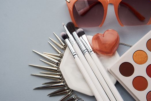 eyeshadow powder blush makeup brushes glasses stand gray background. High quality photo