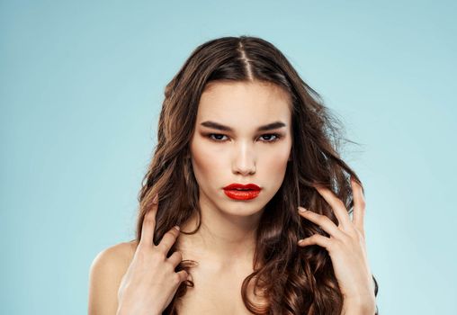 Woman red lips blue background naked shoulders curly hair hairstyle model. High quality photo