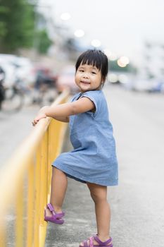 little girl climbing yellow fencein the park