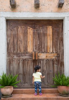 Little girl knocks on the wooden closed door