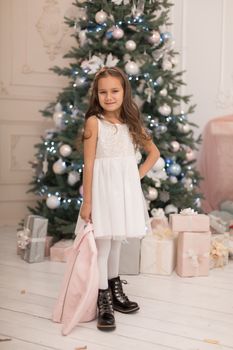 Beautiful little girl posing near the Christmas tree.