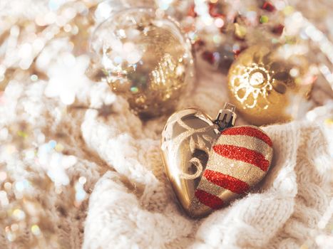 Golden heart for Christmas tree on cable-knit sweater. Decorative symbol of love with red stripes and spangles. Winter holiday spirit. New year celebration.