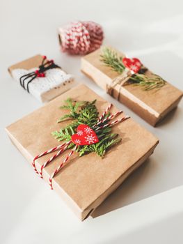 Christmas DIY presents wrapped in craft paper with fir tree branches and red hearts. Decorations on New Year gifts. Festive background. Winter holiday spirit.