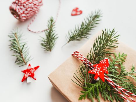 Christmas DIY presents wrapped in craft paper with fir tree branches. Red decorations in shape of Christmas tree. New Year gifts. Festive background. Winter holiday spirit.