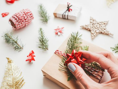 Christmas DIY presents wrapped in craft paper with fir tree branches and red bow. Decorations on New Year gifts. Festive background. Winter holiday spirit.