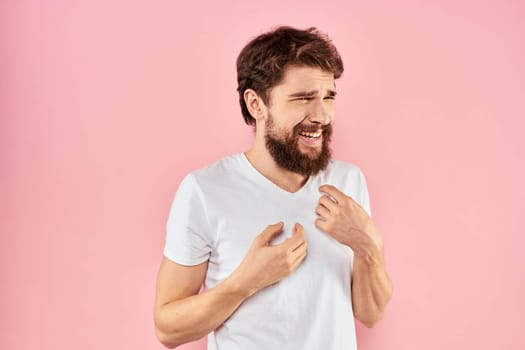 Man in white t-shirt gestures with hands emotions lifestyle cropped view pink background. High quality photo