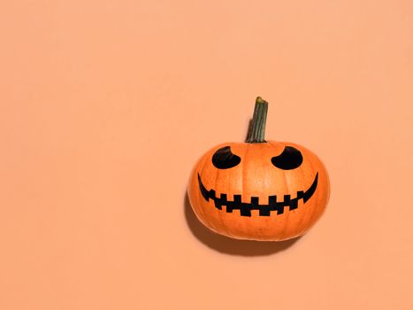 Halloween pumpkin on orange background. Halloween concept with copy space for text or design. Hard light. Jack-o-lantern laughing face on bright orange squash