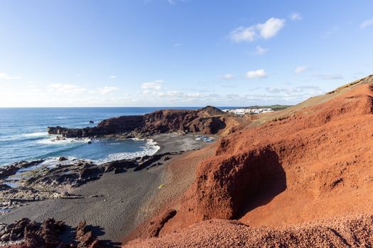 Panoramic view on the coastline of El Golfo with red and black colored volcanic rock formations and lava fields in the southwest of canary island Lanzarote