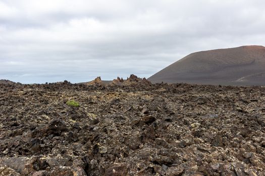 View at volcanic landscape in Timanfaya Nationalpark on canary island Lanzarote, Spain with lava field in the foreground and mountain in the background