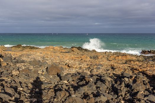 Lava rocks, rough sea and water waves at the coastline of Costa Teguise on Canary island Lanzarote, Spain