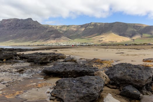 Coastline and sand beach Playa de Famara with mountain range and ocean waves in the north west of canary island Lanzarote, Spain