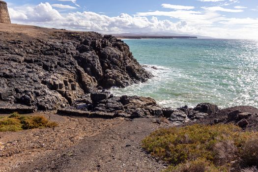 Panoramic view at the coastline of El Cotillo on canary island Fuerteventura, Spain with  lava rocks and mountain range in the  background