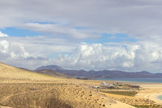 Panoramic view at sandy beach of Risco del Paso on canary island Fuerteventura, Spain  with  turquoise water and mountain range in the background