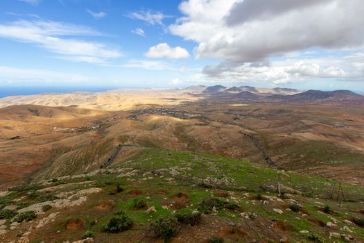 Panoramic view at landscape from viewpoint Mirador Morro Velosa on Fuerteventura, Spain with  green vegetation and multi colored volcanic hills