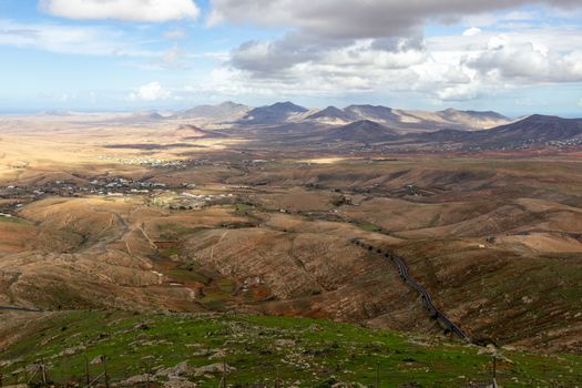 Panoramic view at landscape from viewpoint Mirador Morro Velosa on Fuerteventura, Spain with  green vegetation and multi colored volcanic hills