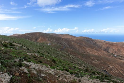 Panoramic view at landscape from viewpoint Mirador Morro Velosa on Fuerteventura, Spain with  green vegetation and multi colored volcanic hills