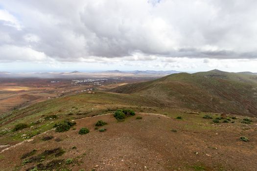 Panoramic view at landscape from viewpoint Mirador Morro Velosa on Fuerteventura, Spain with  green vegetation and multi colored volcanic hills