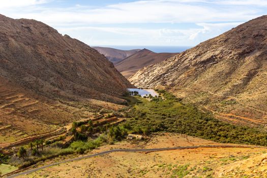 Panoramic view at landscape between Betancuria and Pajara  on Fuerteventura, Spain with dammed lake and multi colored volcanic mountains