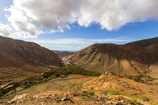 Panoramic view at landscape between Betancuria and Pajara  on Fuerteventura, Spain with dammed lake and multi colored volcanic mountains