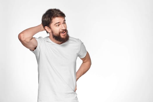 Bearded man in white t-shirt gesture with hands emotions light background. High quality photo