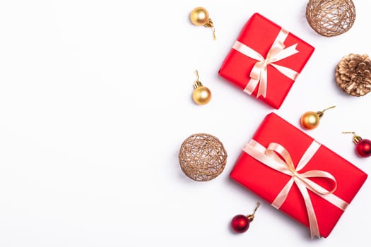 Christmas composition. Red gift box, pine cones, gold and red ornament decorations on white background. Winter holidays concept. Top view copy space