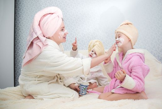 Portrait of woman and her daughters doing doing spa treatments in the bedroom.