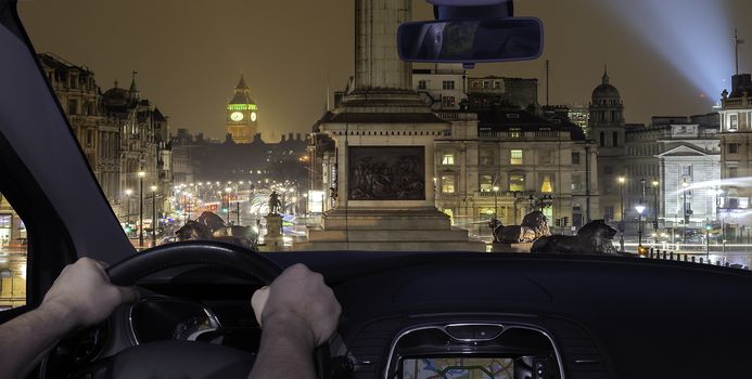 Driving a car in Trafalgar Square at night with the Big Ben on the background, London, UK
