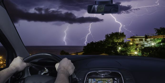 Driving a car towards a spectacular lightning storm over the sea