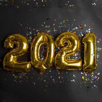 2021 concept new year from golden foil balloon and confetti on black background stock photo