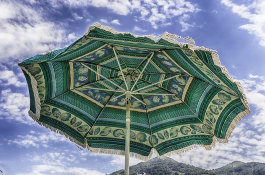 Decorated green beach umbrella as seen from the ground against the background of a light sky