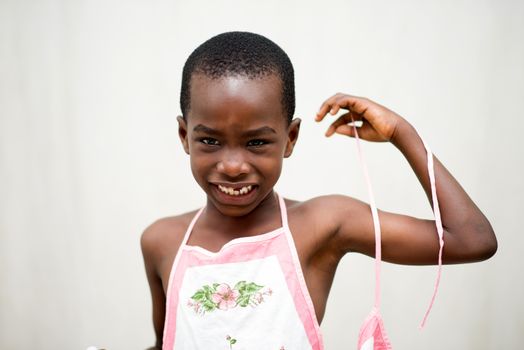 little smiling boy standing shirtless in studio in white and pink apron.