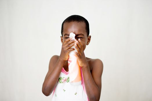 smiling little boy standing in studio and wearing apron plays with bottle of liquid soap