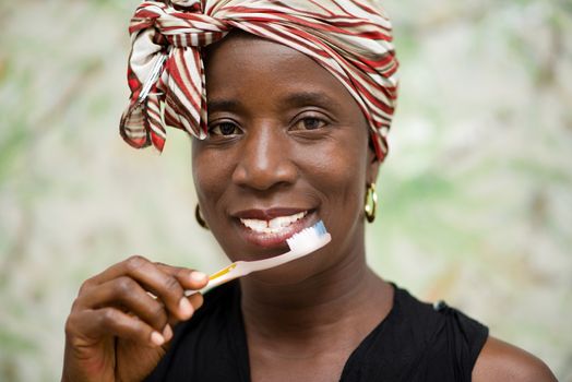 young smiling woman wearing a scarf on the head brushes the tooth