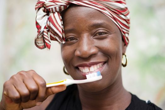young smiling woman wearing a scarf on the head brushes the tooth