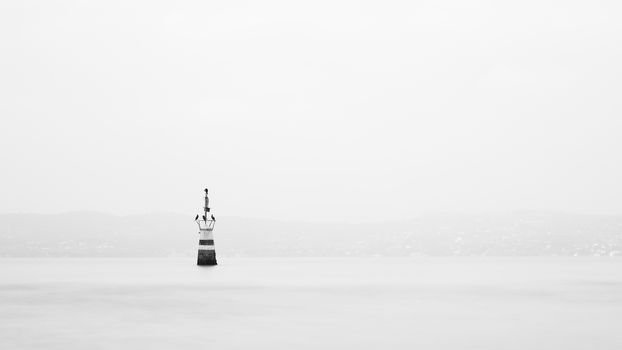 The view past a marker post across Lake Garda from the resort town of Sirmione in North East Italy.  Sirmione is at the southern end of the lake which is in North East Italy.