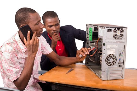 young computer technician talking on the phone and repairing a computer in front of an instructor