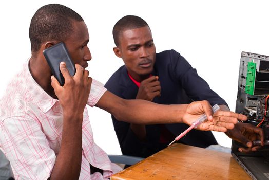 young computer technician talking on the phone and repairing a computer in front of an instructor