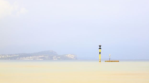 The view past a marker post across Lake Garda from the resort town of Sirmione.  Sirmione is at the southern end of the lake which is in North East Italy.