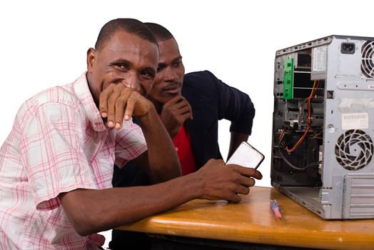 two technicians sitting at the desk working together on a computer
